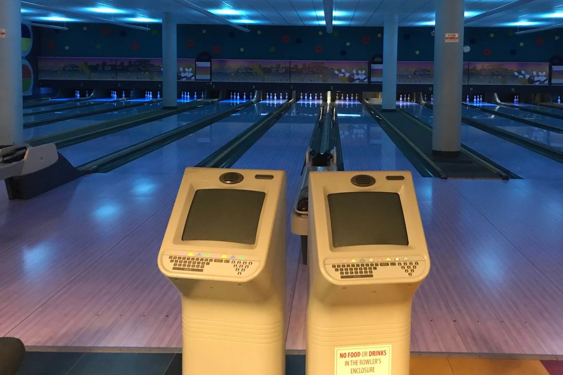 Allées du Chinook Bowladrome à Calgary, éclairées en bleu, avec les consoles de pointage au premier plan.